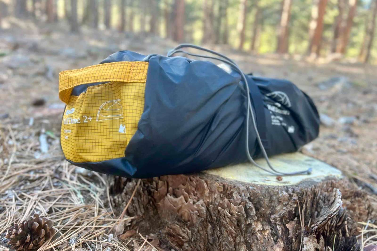 a packed up tent sits on a log