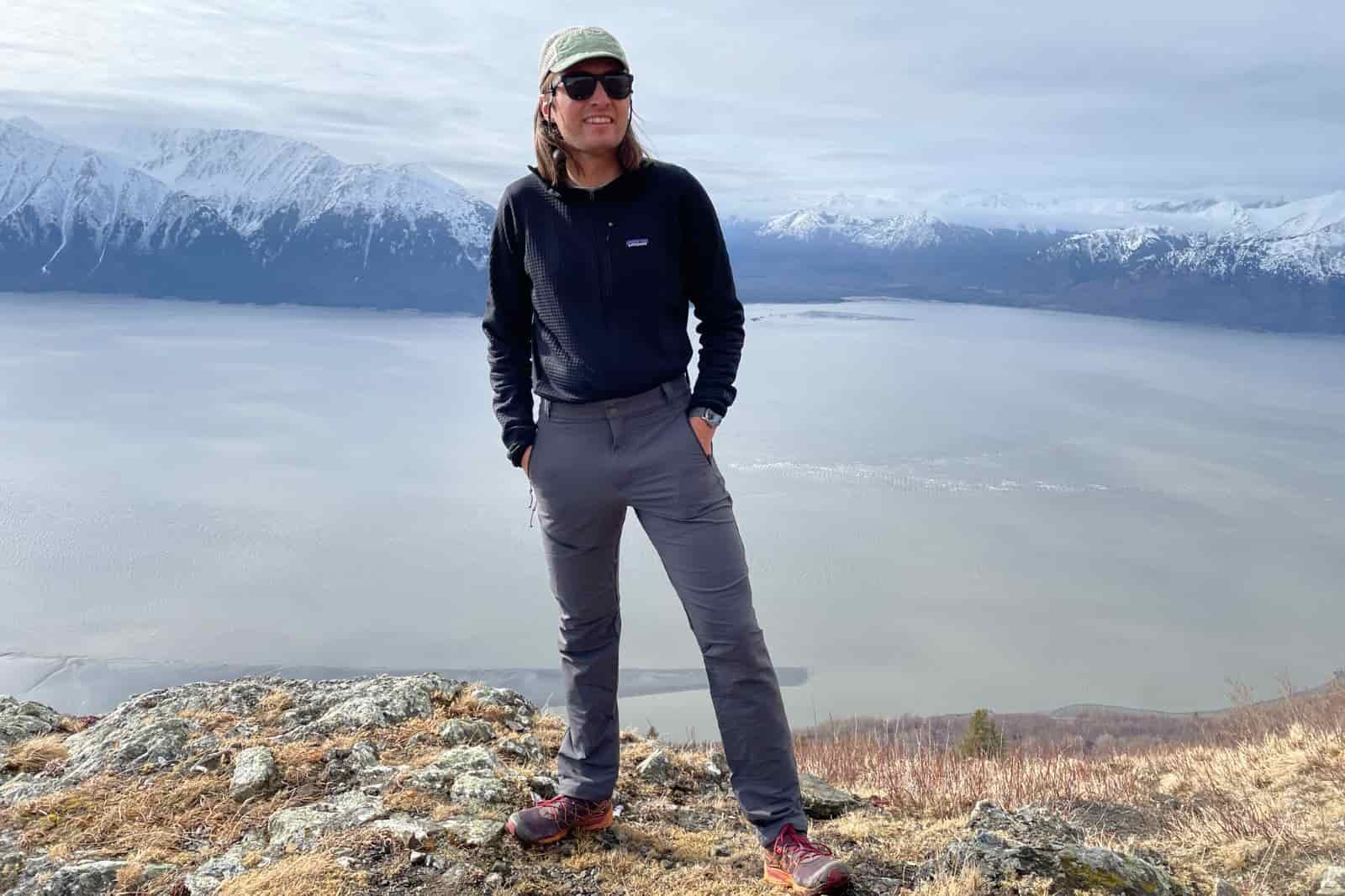 A man stands with a mountain and ocean view.