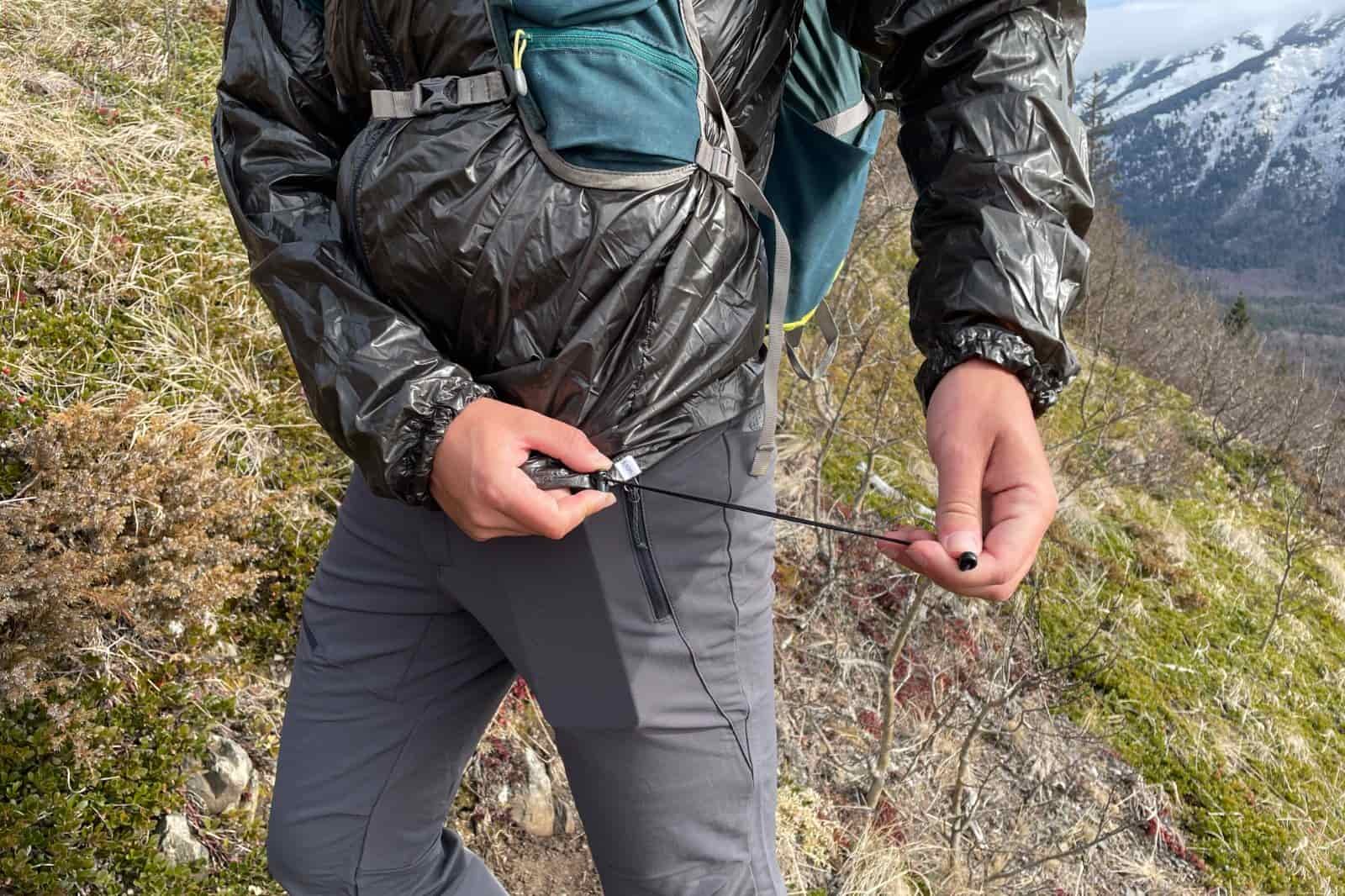 A man cinches down the hem of his windbreaker.