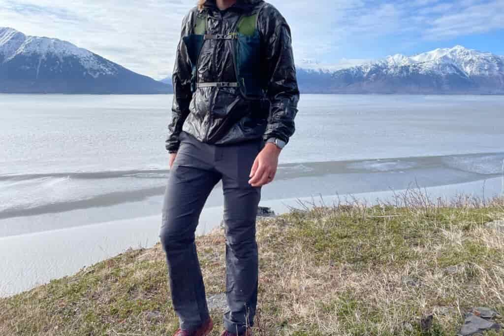 A man walks along a trail with a mountain view.