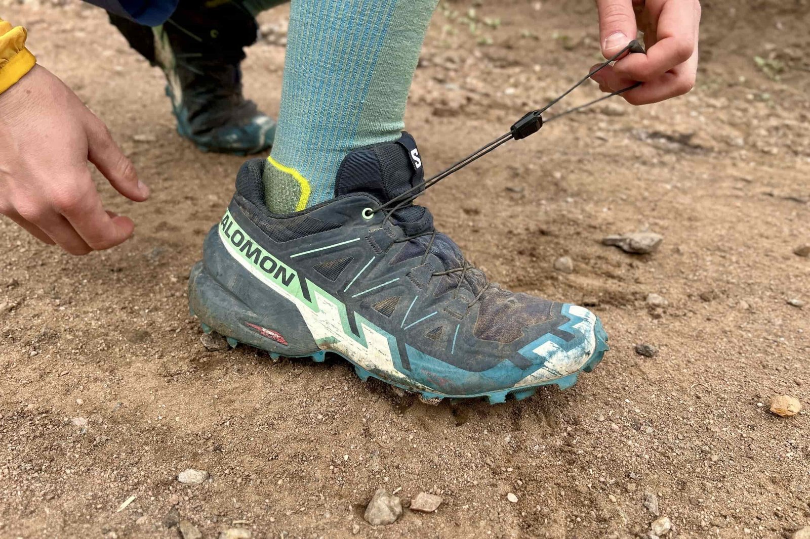 Close up of a person adjusting the lacing pattern on a pair of trail runners.