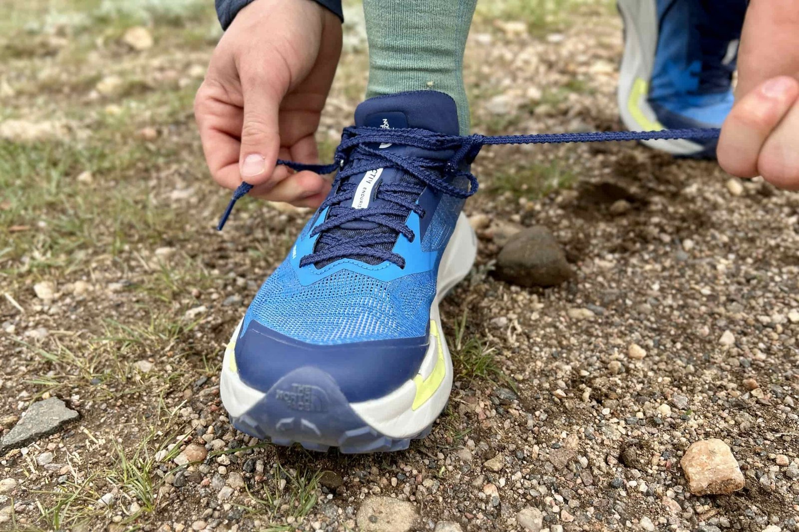 Close up of a person tying the shoelaces on a pair of trail runners.