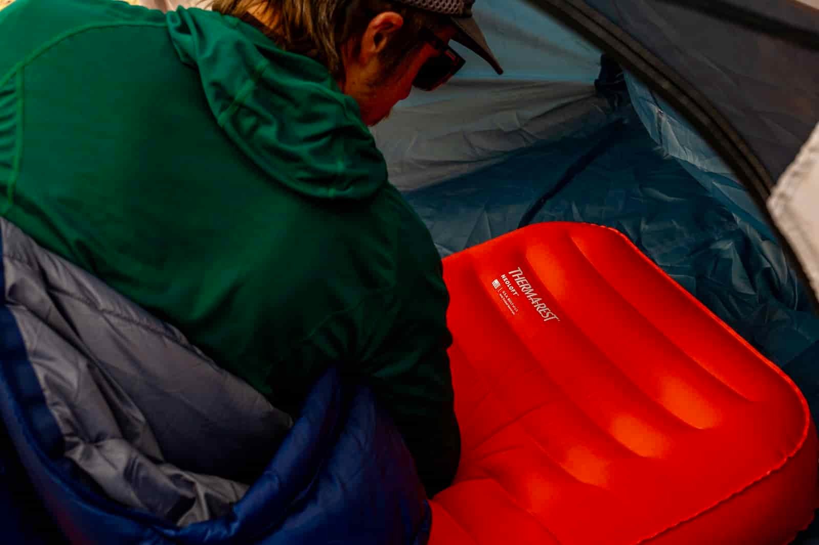 a hiker lays on a sleeping pad and looks at the logo