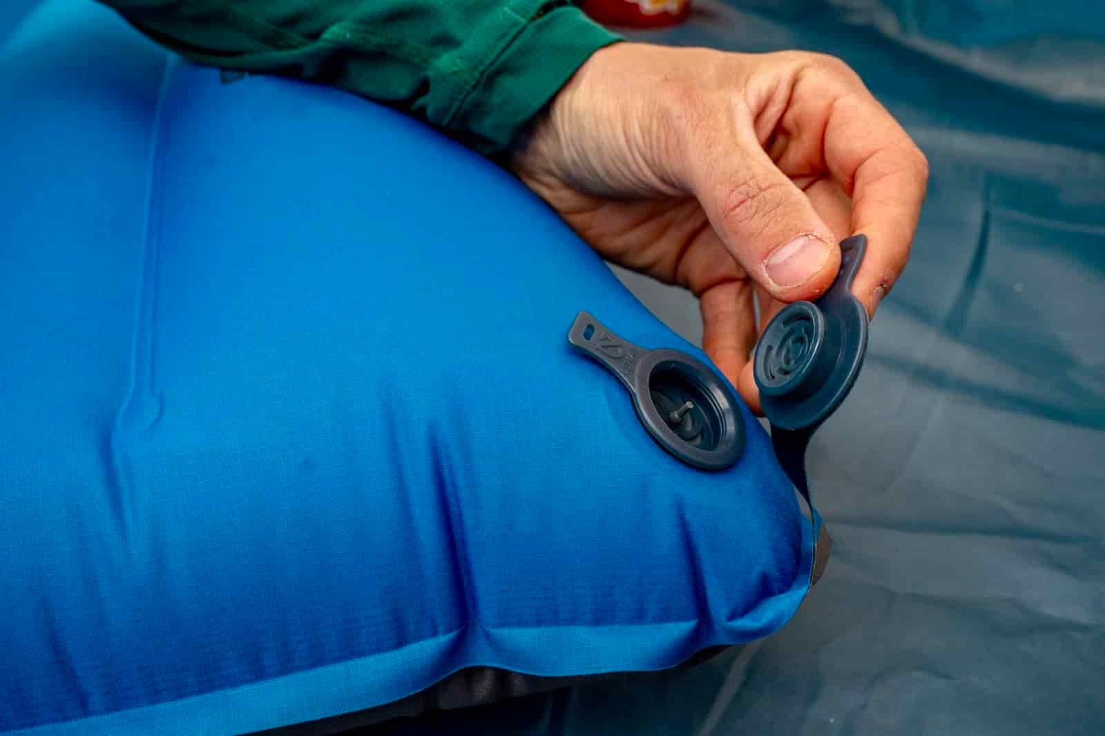 a closeup of a hiker opening the air valve on a sleeping pad