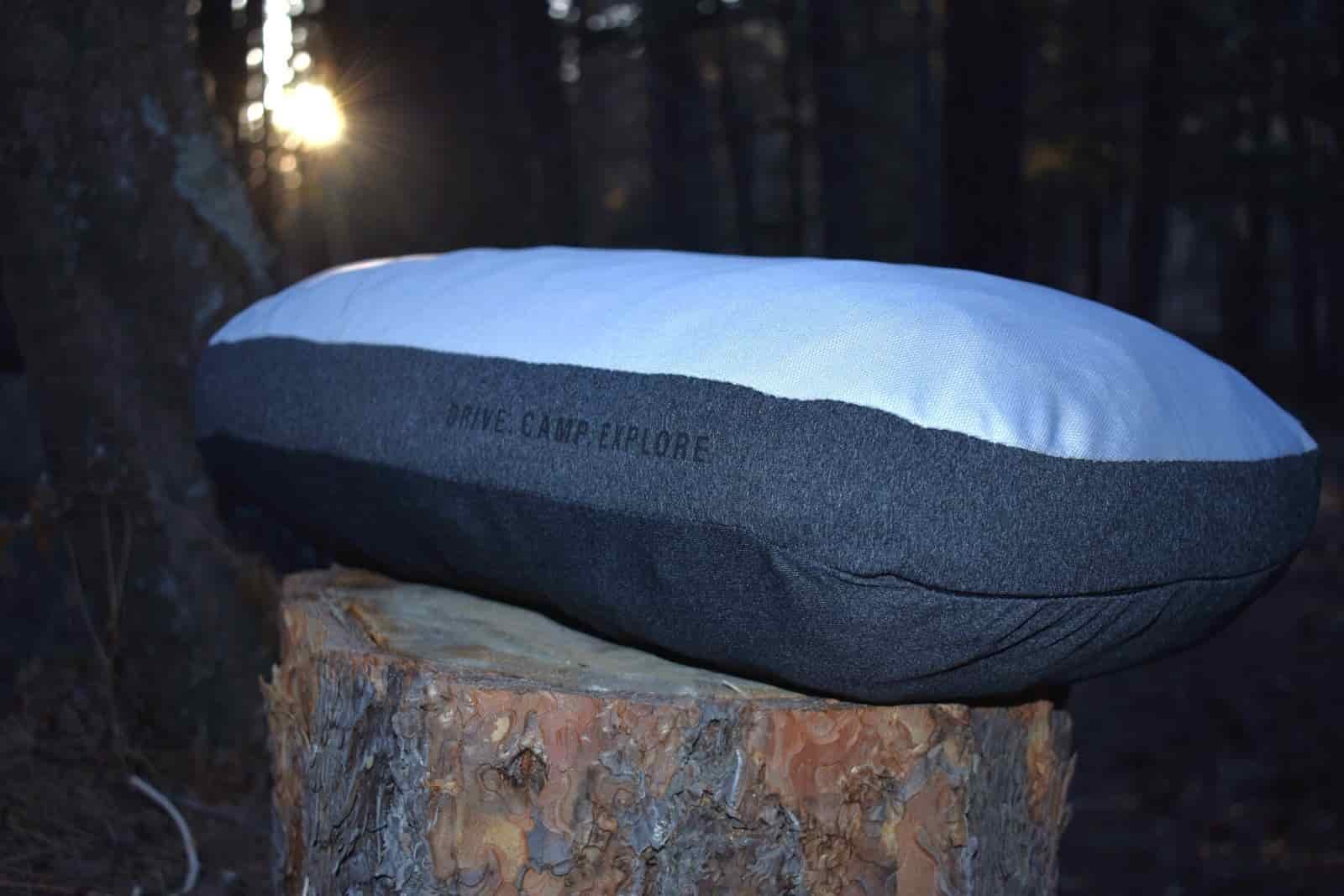 Pillow sitting on a stump in the woods with the sun setting in the background
