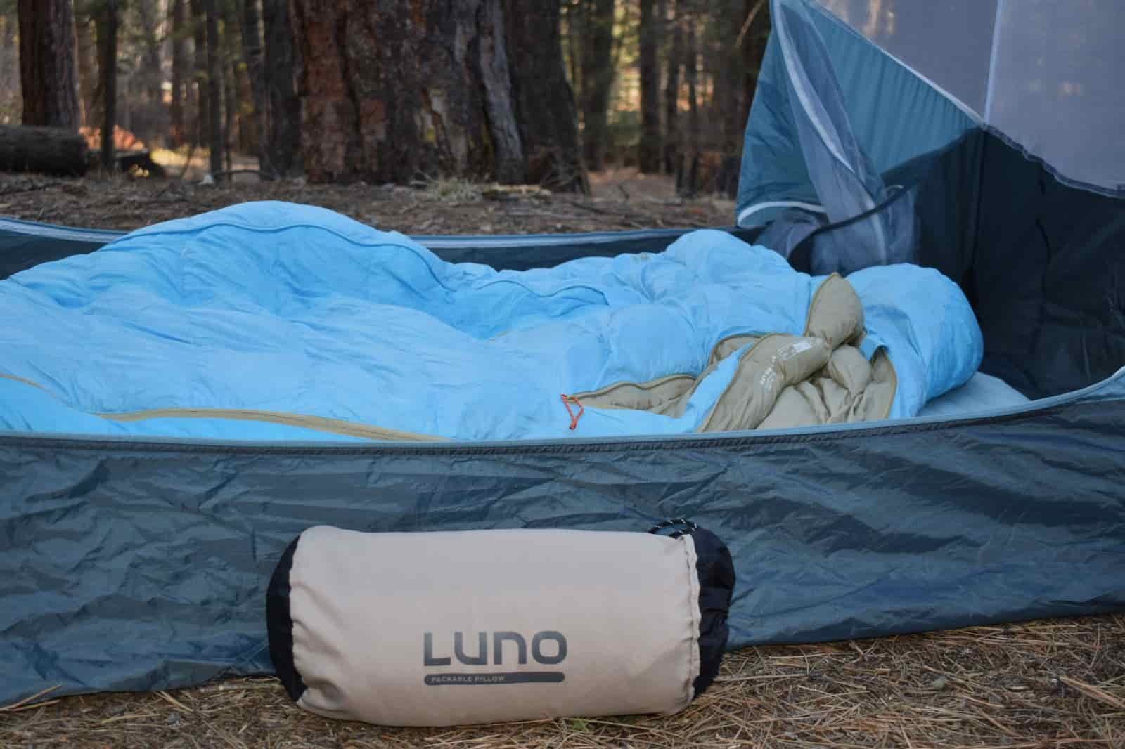 A pillow in a stuff sack sits in front of a test in a campground