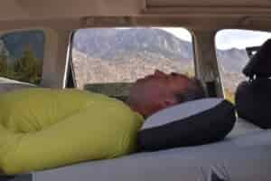 A male hiker rests in his vehicle on an inflatable mattress made to fit his vehicle