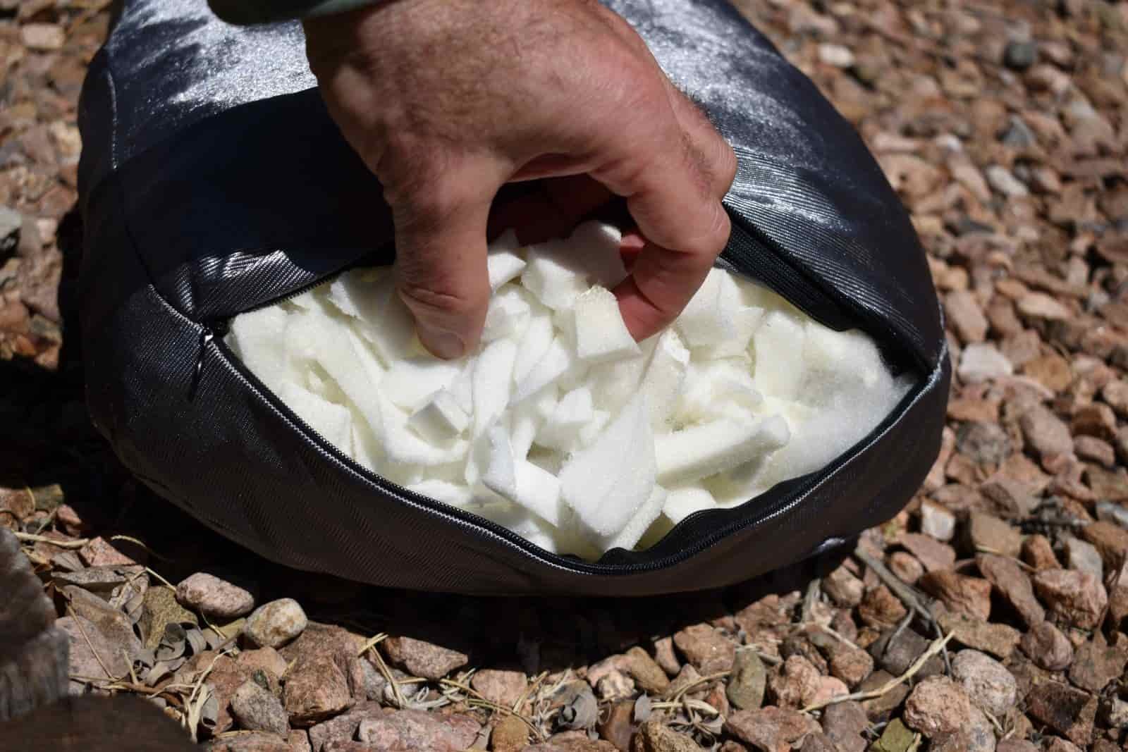 close up of a hand reaching inside a pillow to feel its shredded memory foam