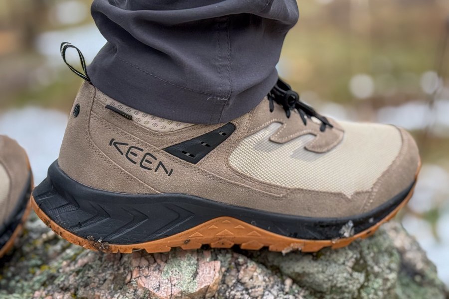 Hiker planting boots on Colorado granite mixed with snow and new spring growth.
