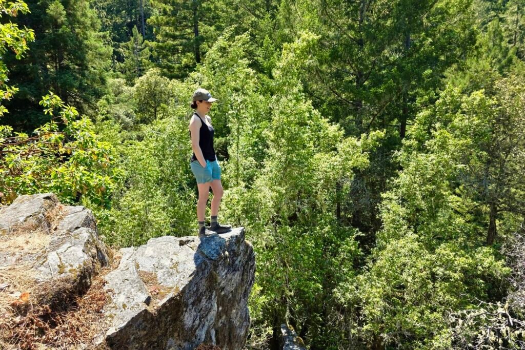 Woman standing on a rock outcropping overlooking the scenery below.