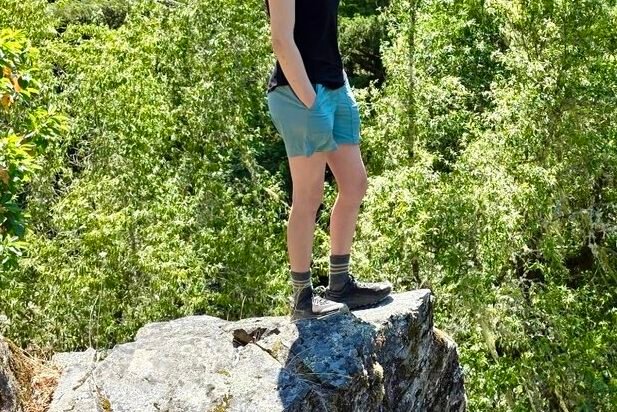 Woman standing on a rock outcropping overlooking the scenery below.