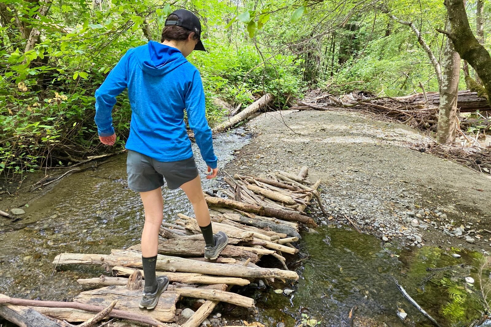 Woman walks across a wooden bridge over a creek.