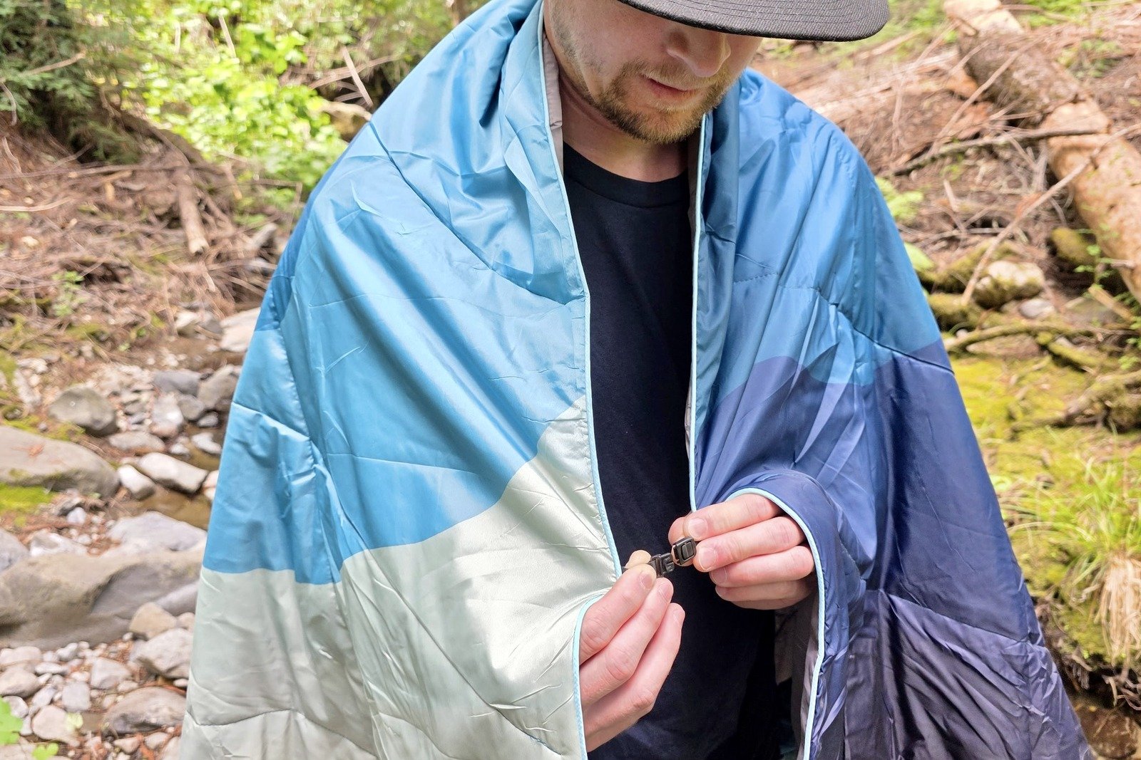 A man clips together a blanket around his shoulders using its cape clip feature.