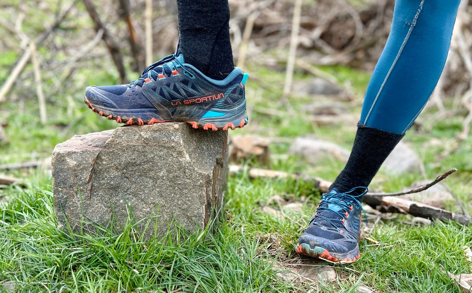 Image of a person from the knees down wearing leggings and trail runners while posing on a rock.