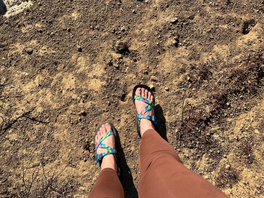 A woman walking along a dirt trail wearing Chaco Z/1 Classic hiking sandals.