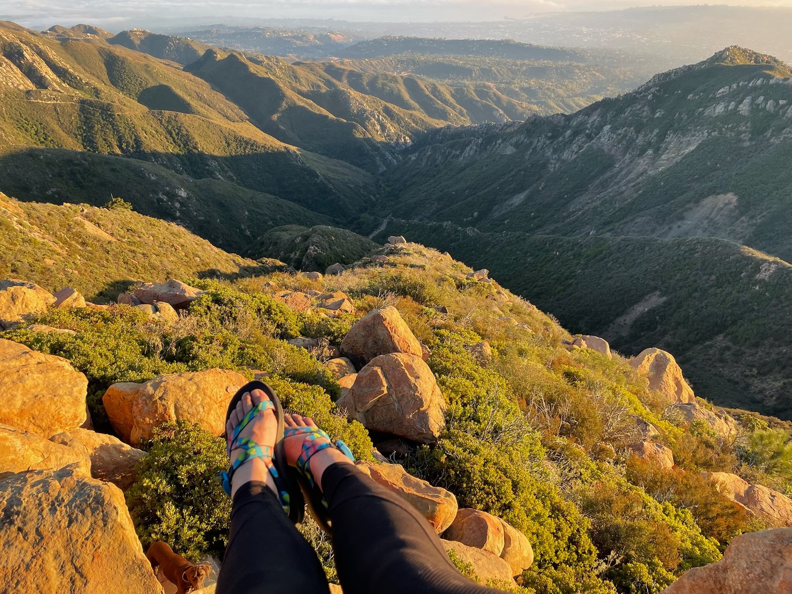 A woman's feet in Chaco Z/1 Classic hiking sandals in a rocky, mountainous environment.