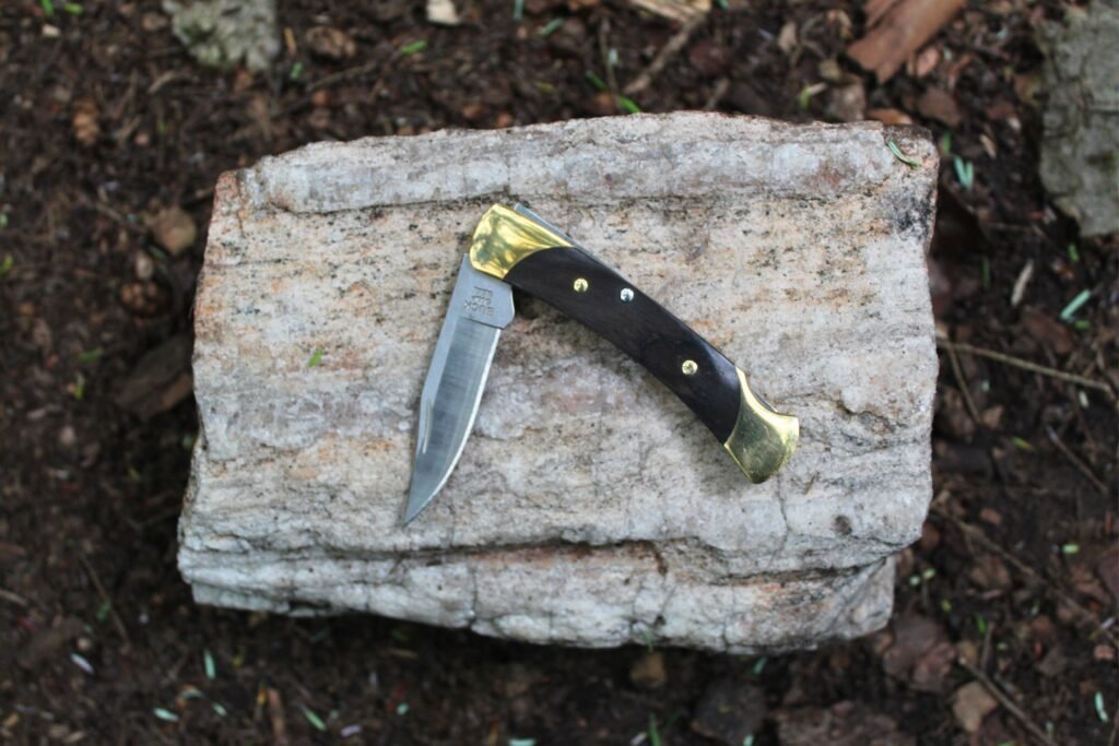 The Buck Knives 055 Pocket Knife halfway open on a rock