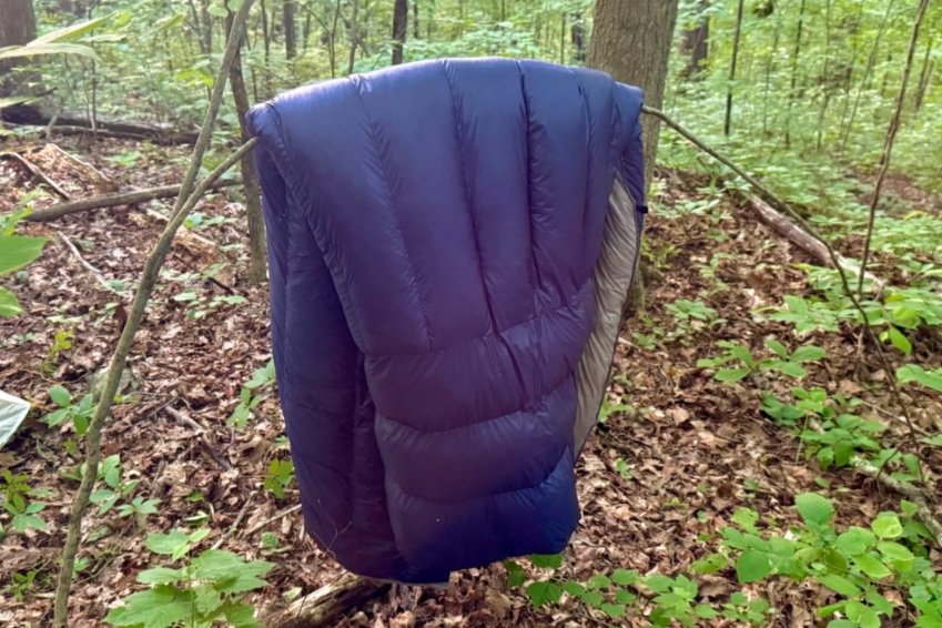 Hyperlite Mountain Gear 20-Degree Quilt hanging on a tree branch in the woods