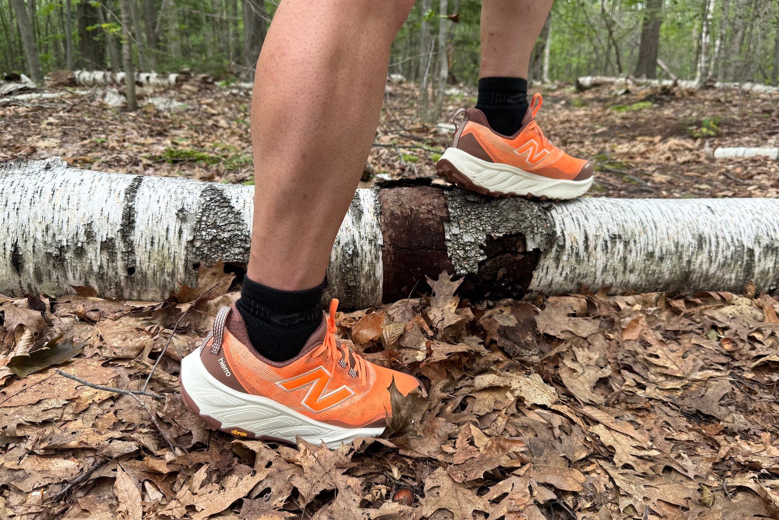 Close up of orange New Balance Fresh Foam Hiero 9 with a birch tree