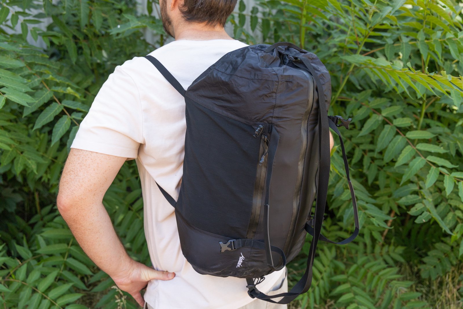 A man wears the Matador Freefly Packable Duffel as a backpack after repositioning the exterior compression straps.