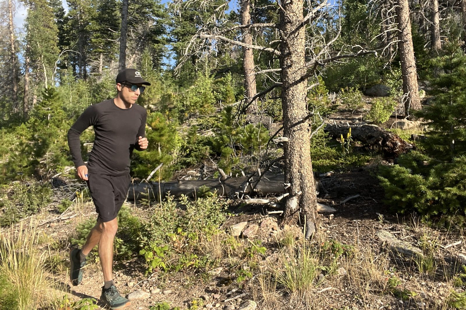 a runner runs along a wooded trail in a black base layer.