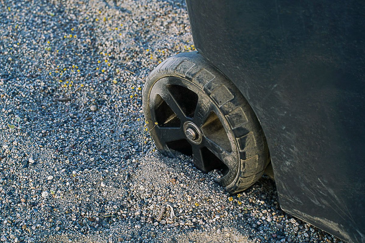 A close up of a single wheel on the YETI Roader 48 cooler. The wheel is partially submerged in sandy ground.