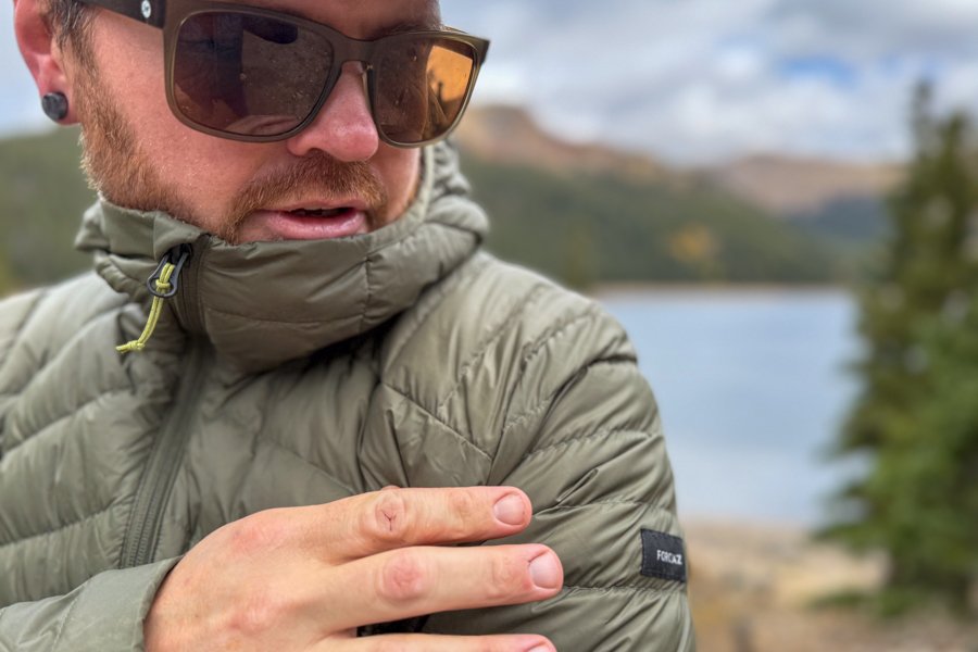 Close-up of the Simond MT100’s collar and sleeve, with the wearer adjusting the fabric to show the Forclaz logo patch.