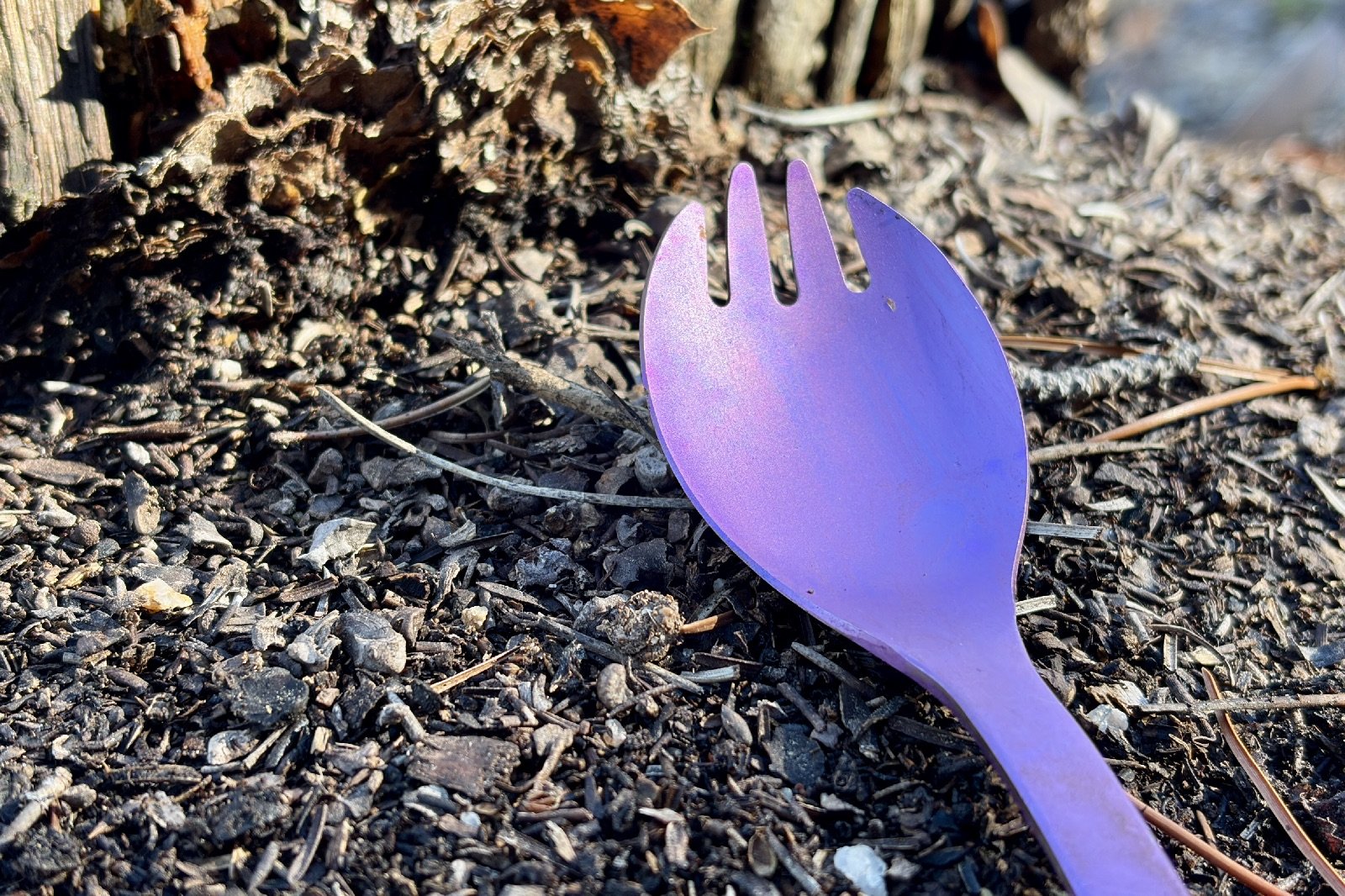 a close up of a purple spork on dirt