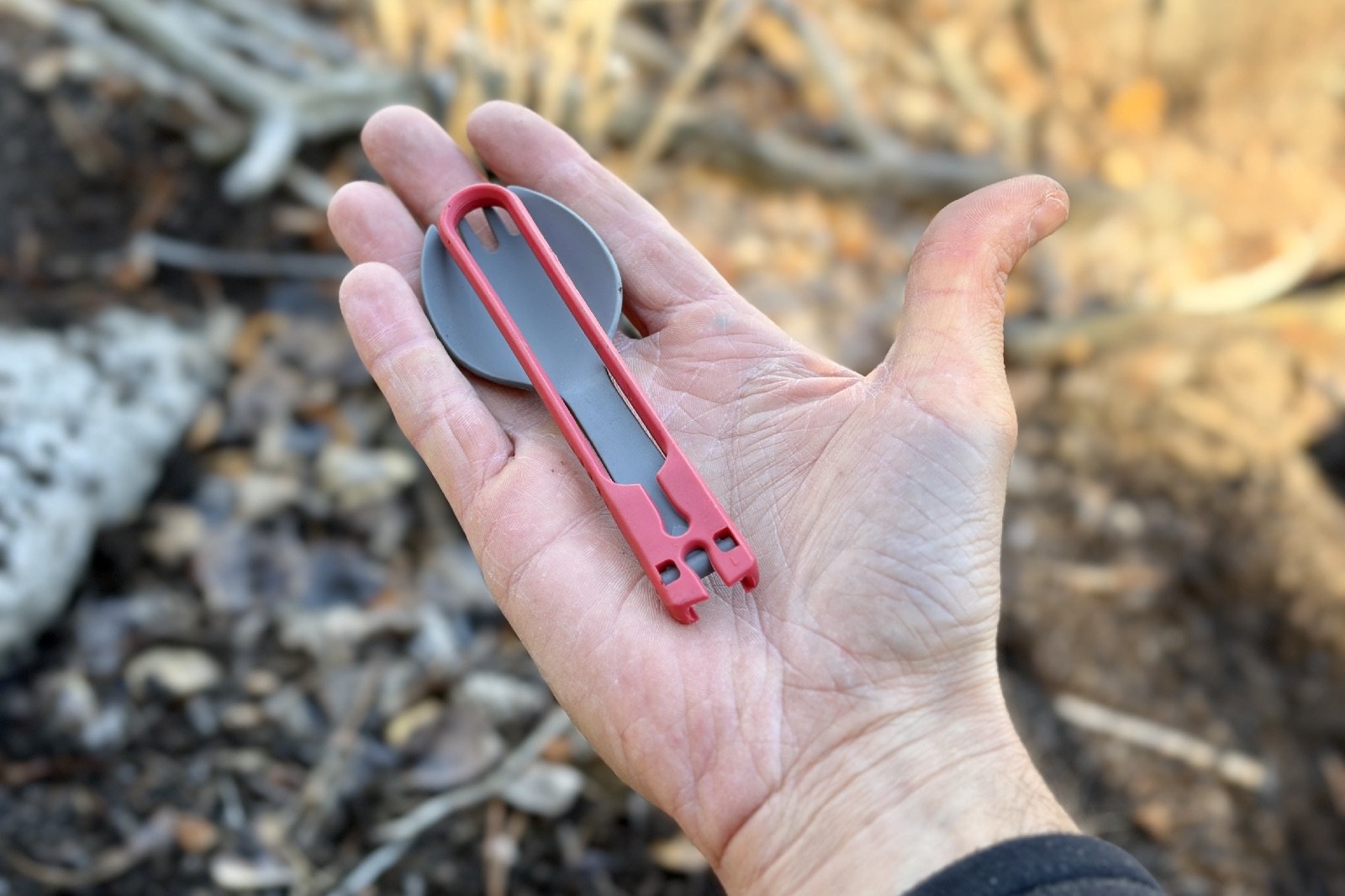 a folding plastic spork in the palm of a hand
