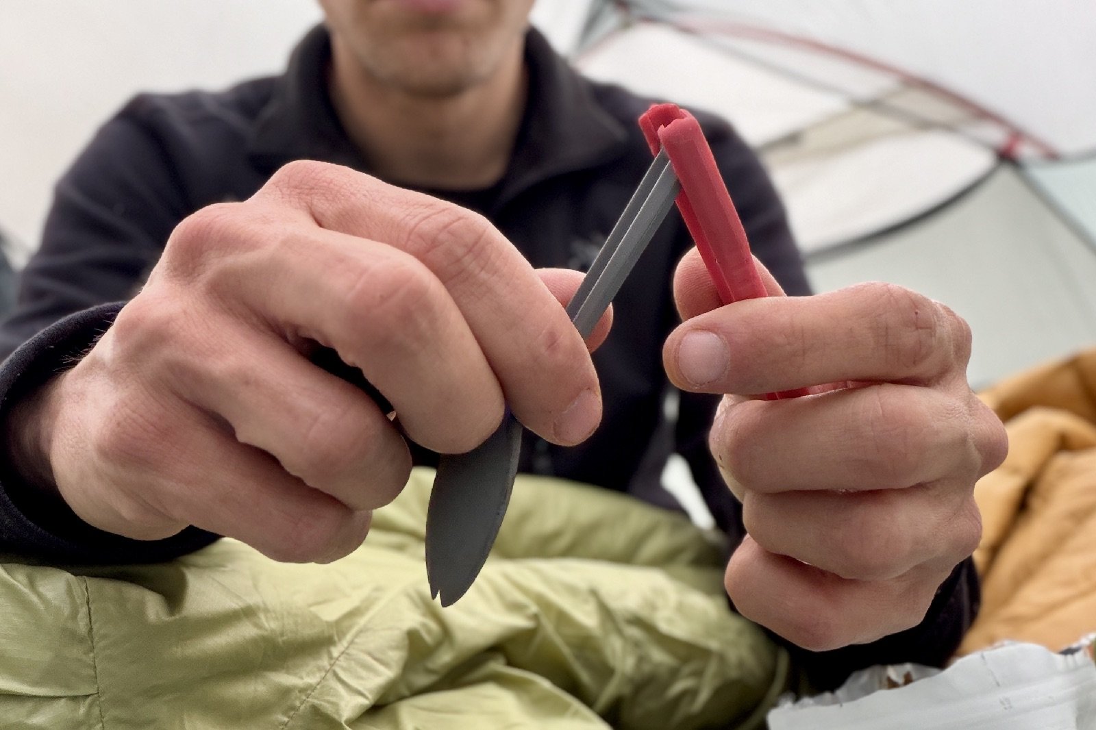 a hiker folds a plastic folding spork close to the camera