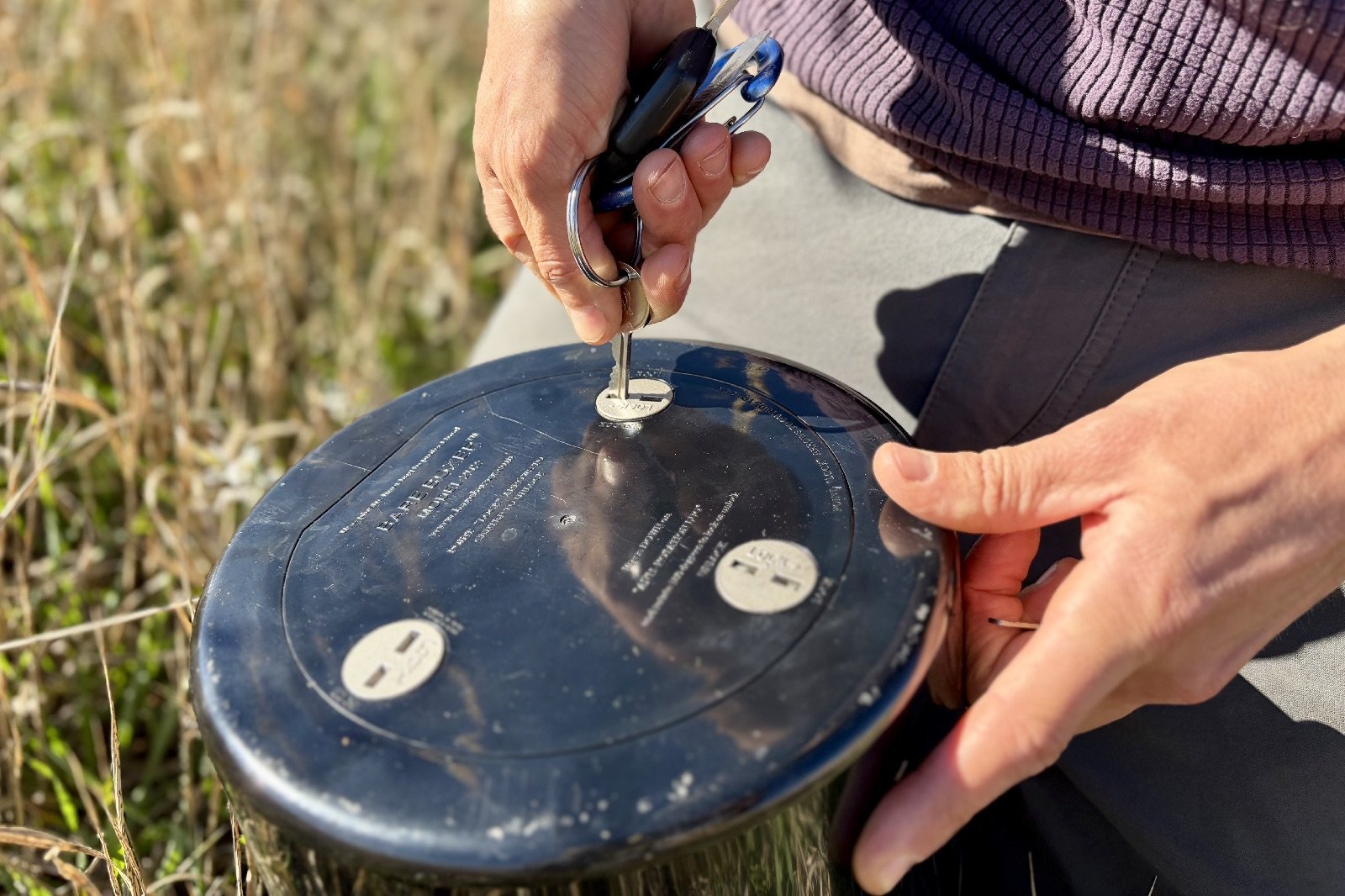 a close up of a hiker ulnocking a bear canister with a set of common keys