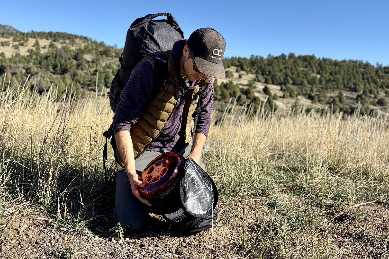 a hiker slides a bear canister into its carrying case