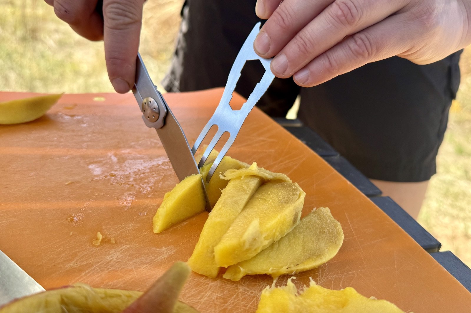 a close up of someone cutting a mango with a fork and knife