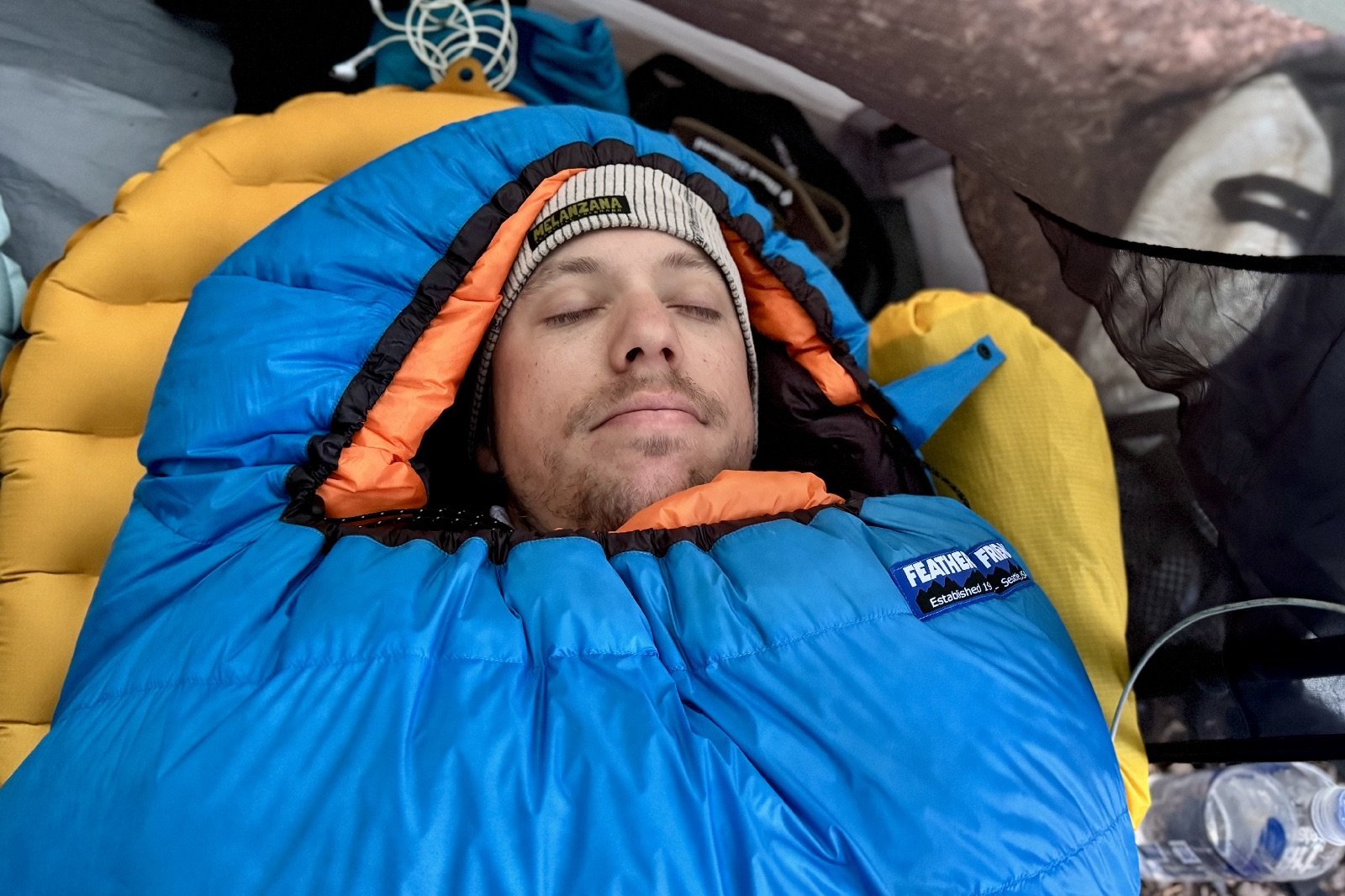 a shoulder up view of a hiker laying in a blue sleeping bag in a tent