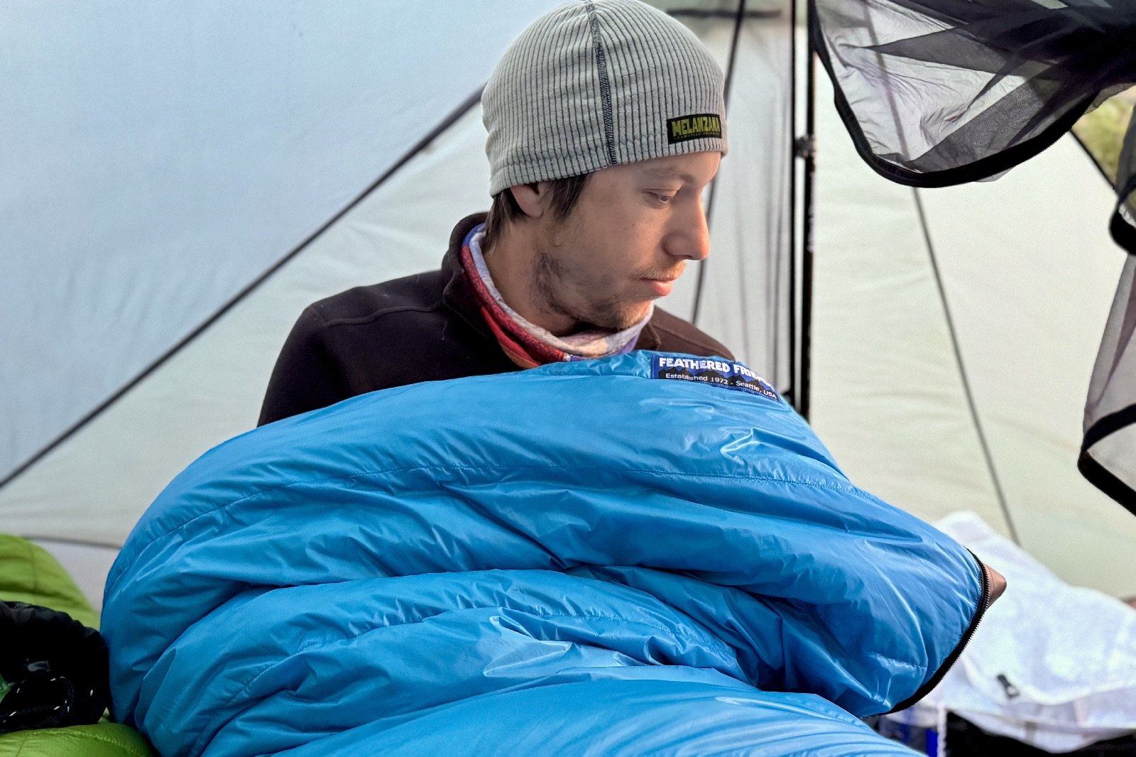 a hiker sits up in a blue sleeping bag in a tent