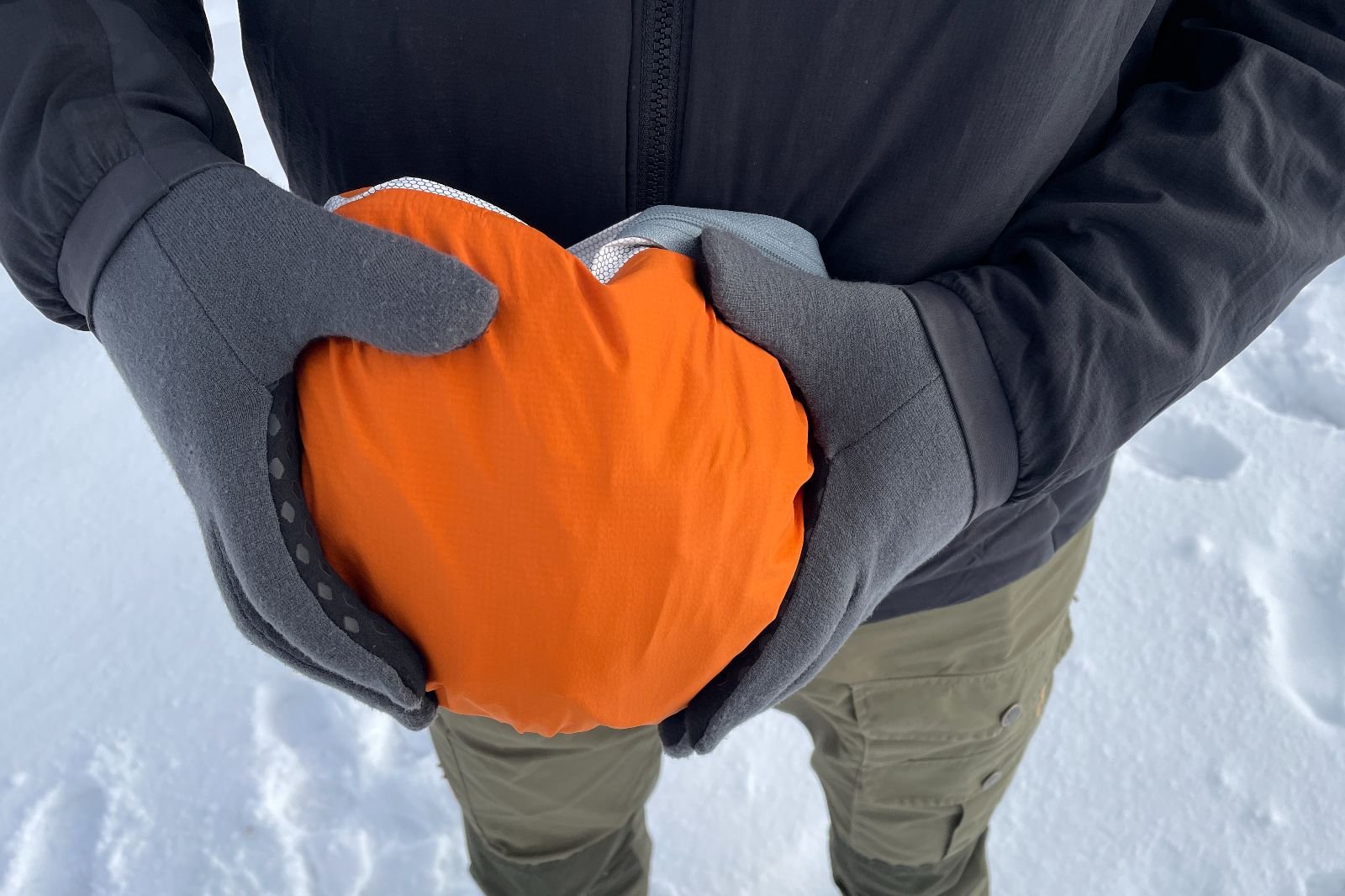 A closeup of an orange rain jacket zipped it its pocket.