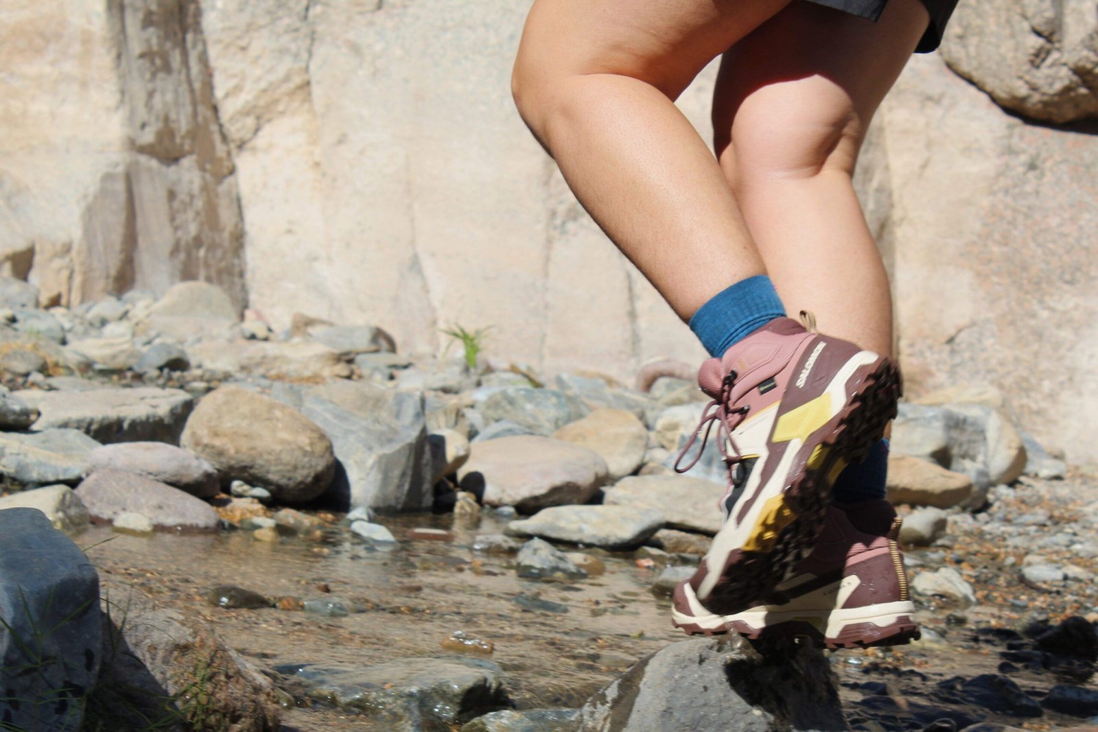 Hiker walking through a shallow stream wearing the Salomon X Ultra 5 GTX Women's Hiking Boots