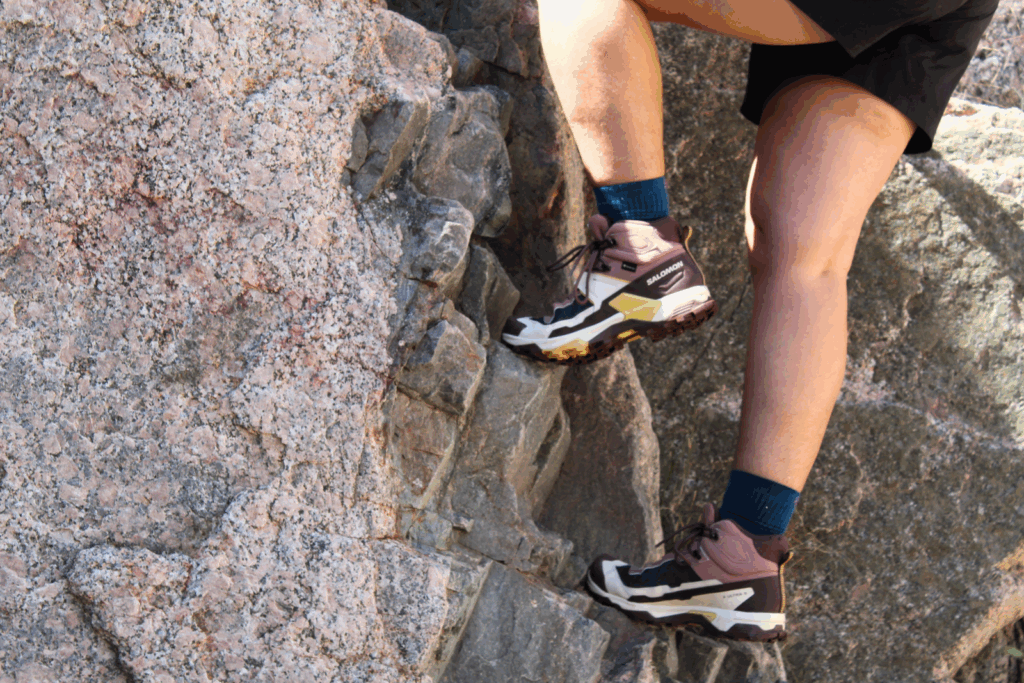 Hiker scrambling up some rocks wearing the Salomon X Ultra 5 GTX Women's Hiking Boots