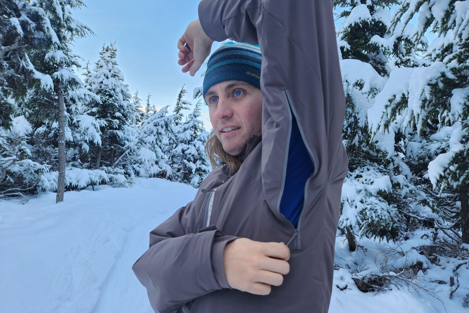 A man unzips the arm vents of his winter jacket.