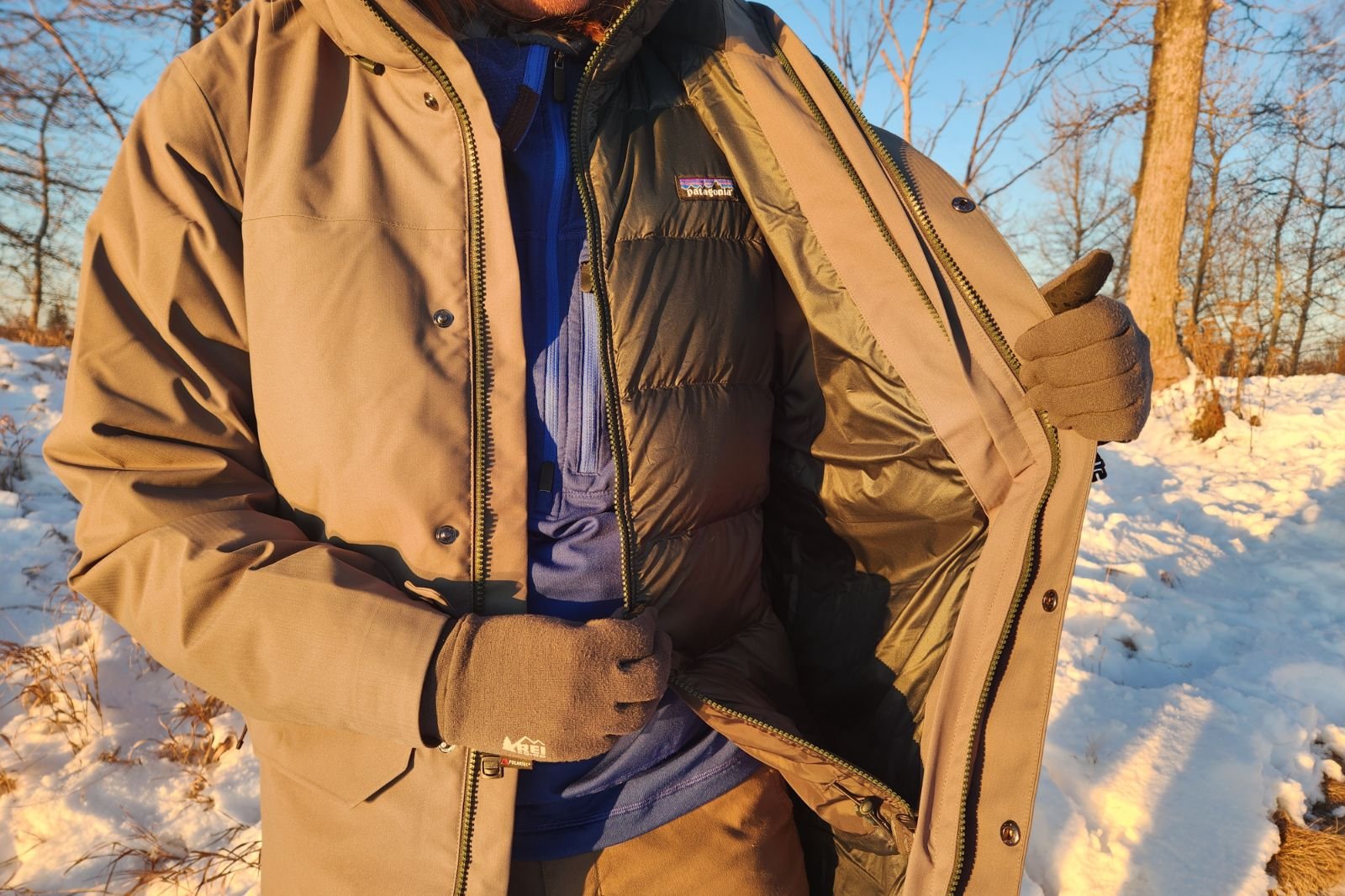 A man unzips the inner lining from his modular jacket.