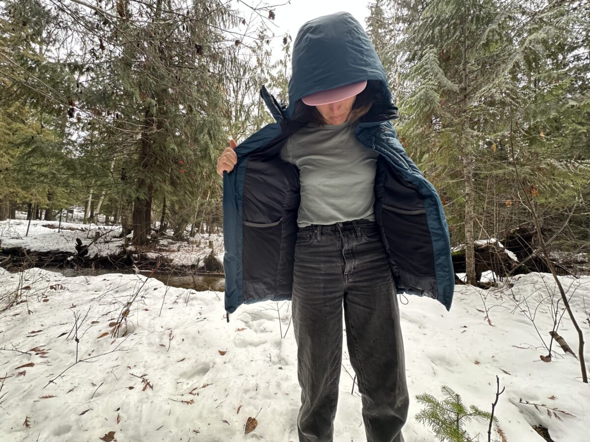 women with unzipped blue down jacket in a snowy forest